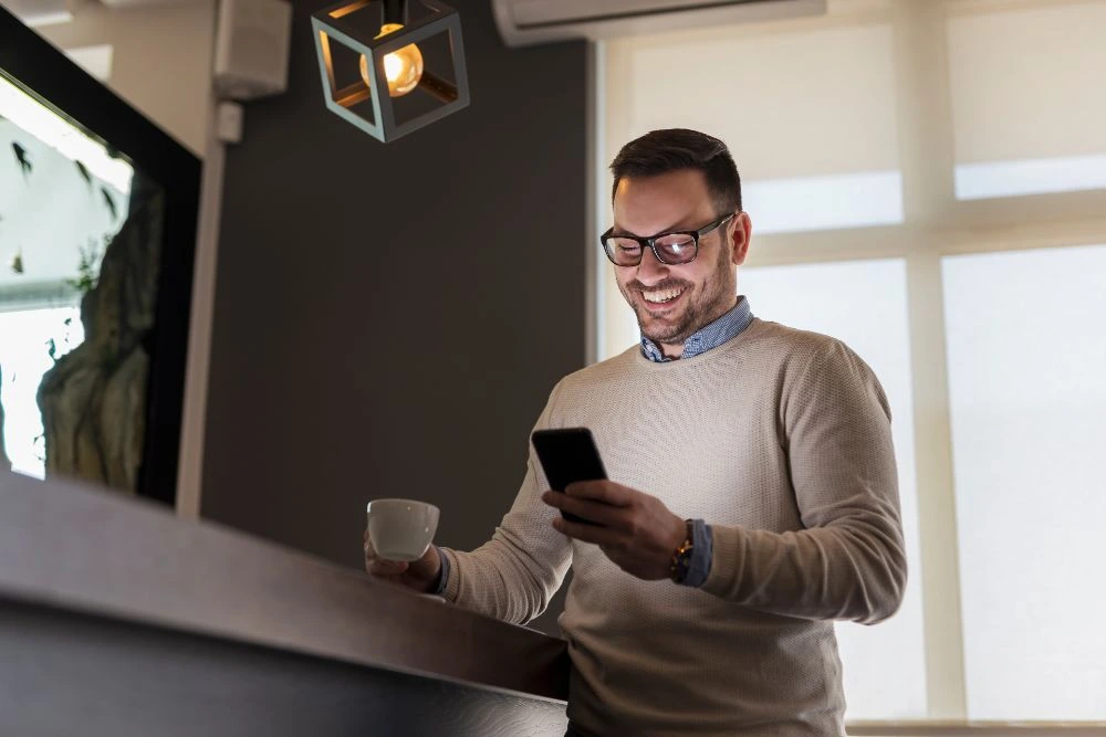 A man wearing glasses is holding a phone and intently looking at its screen.