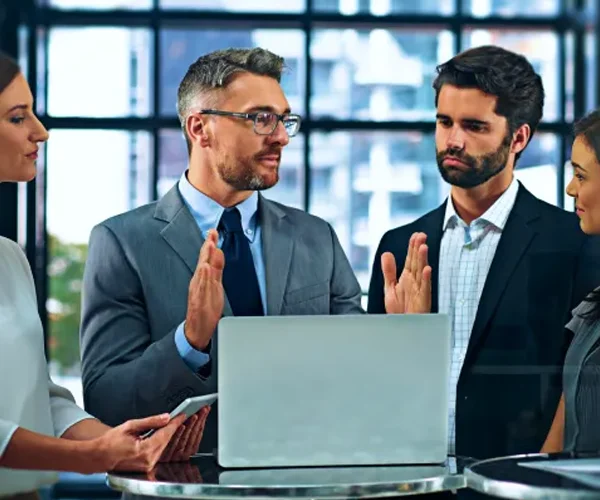Business team discussing strategies around a laptop in an IT consulting session