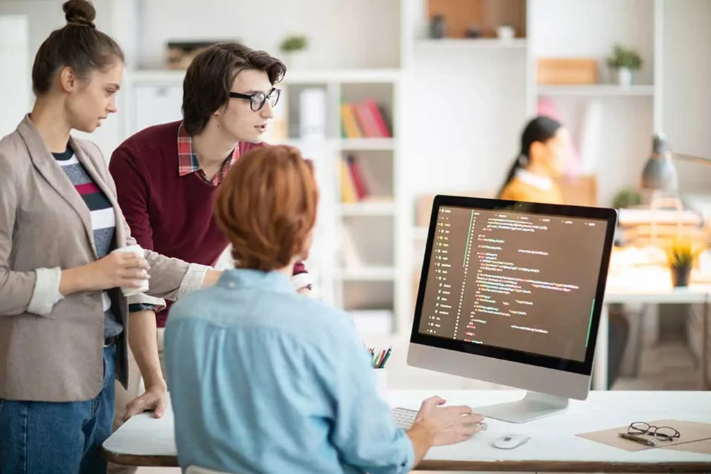 Colleagues working together at a computer in an office, engaged in website development