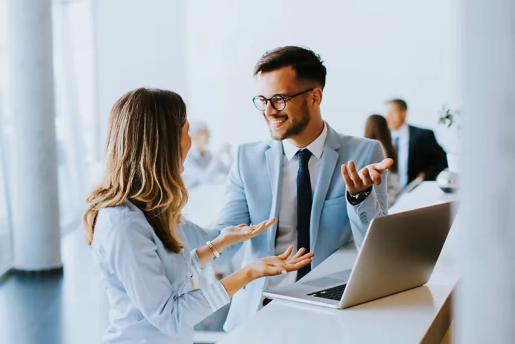 Man and woman engage in conversation at a desk, discussing transparent pricing and expert consultation services