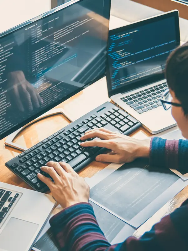 Man engaged in technology solutions, using a laptop and keyboard while working on software development tasks