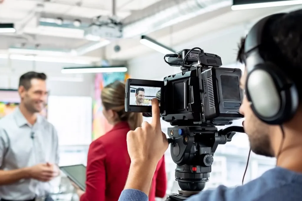 Man filming a video in an office setting, focused on his videography work with a camera and tripod