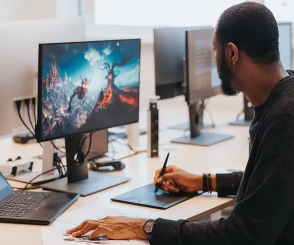 Man focused on game development, working on a computer with two monitors in front of him