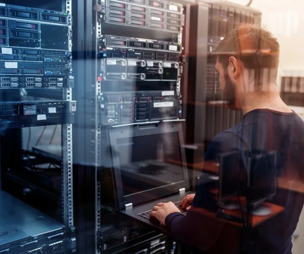 Man stands in front of a server rack, overseeing IT networks and equipment in a data center environment