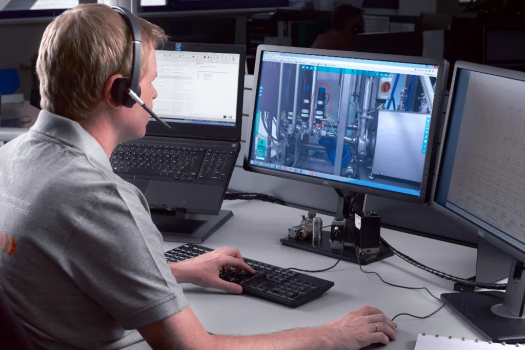 Man wearing headphones is engaged with two computer screens, handling tasks for Remote Services and Regional Offices