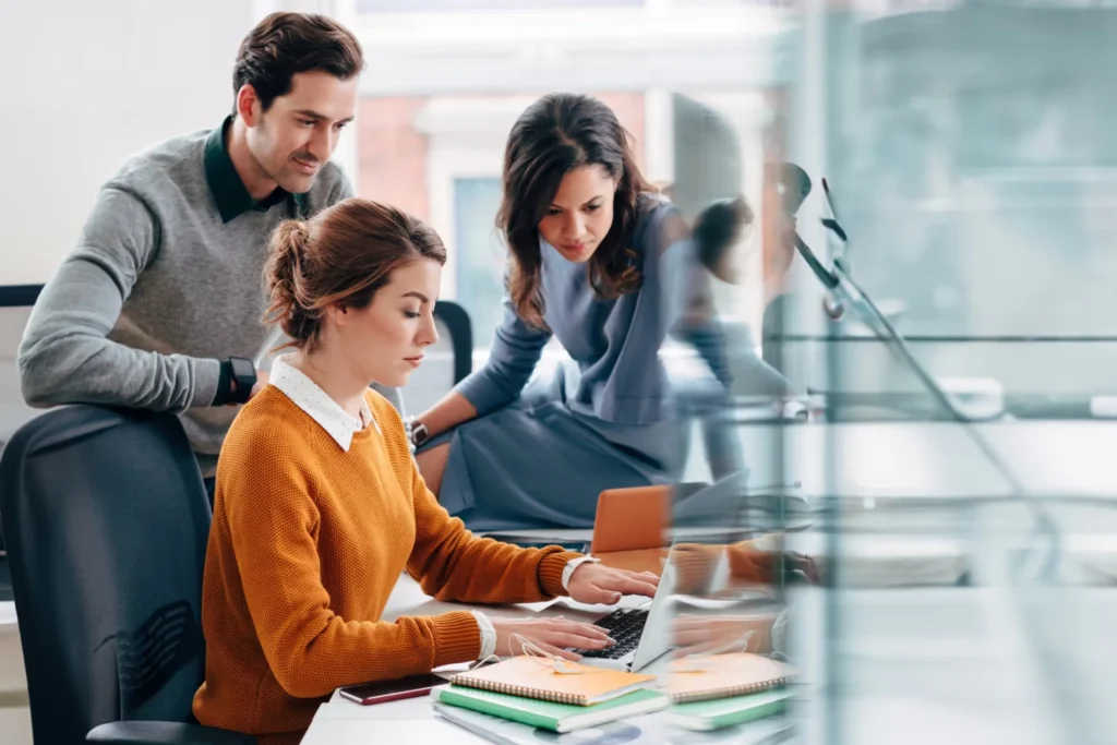 Colleagues collaborating on a laptop in an office setting, focused on staff augmentation services