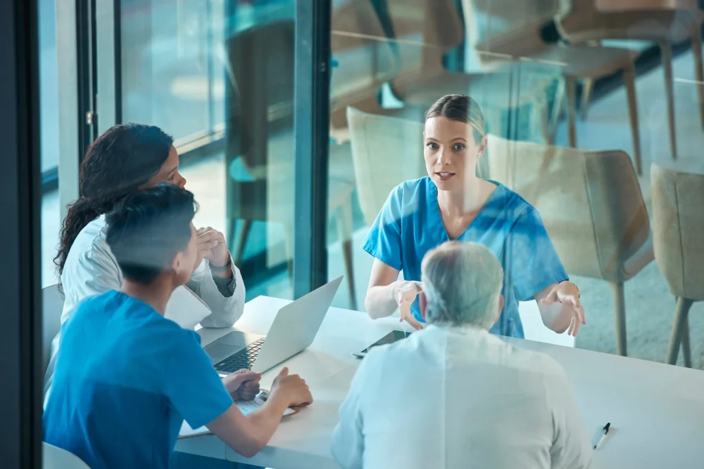 Diverse group of individuals seated at a table with a laptop, working together on healthcare and FinTech IT solutions