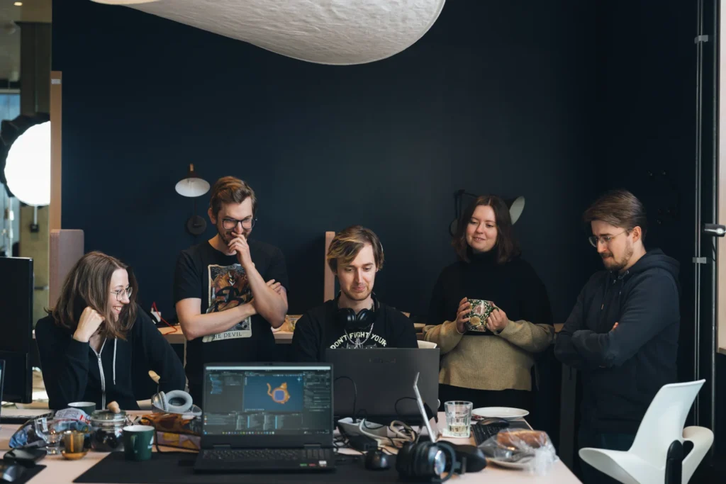 Group of people gathered around a table, each using laptops, engaged in multiplayer and social gaming activities