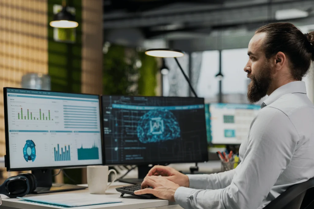 Man at a desk with dual monitors, engaged in tasks involving secure and scalable infrastructure solutions