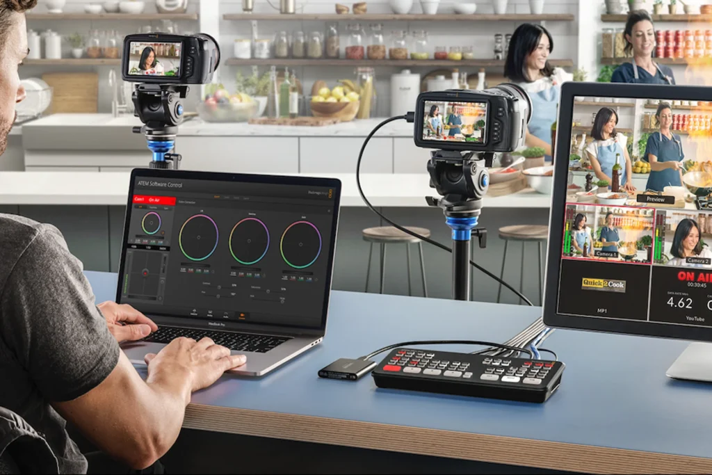 Man operates a laptop while setting up a video camera for live streaming