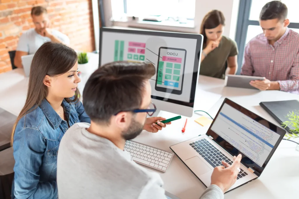 Team members working together on a laptop in an office, engaged in developing a custom e-commerce platform