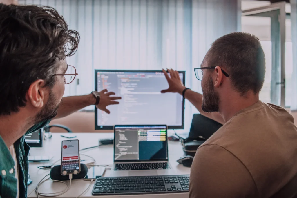 Two men collaborating on a computer in an office, focusing on seamless technology integration