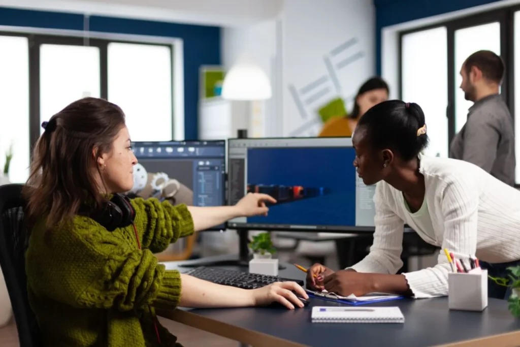 Two women engaged in a computer task in an office, working on training and educational animations together