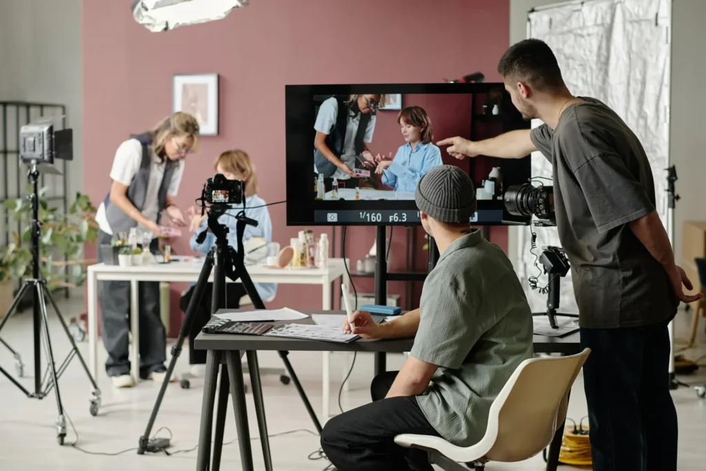 A group of people in a room with a camera and television, collaborating on a healthcare production project